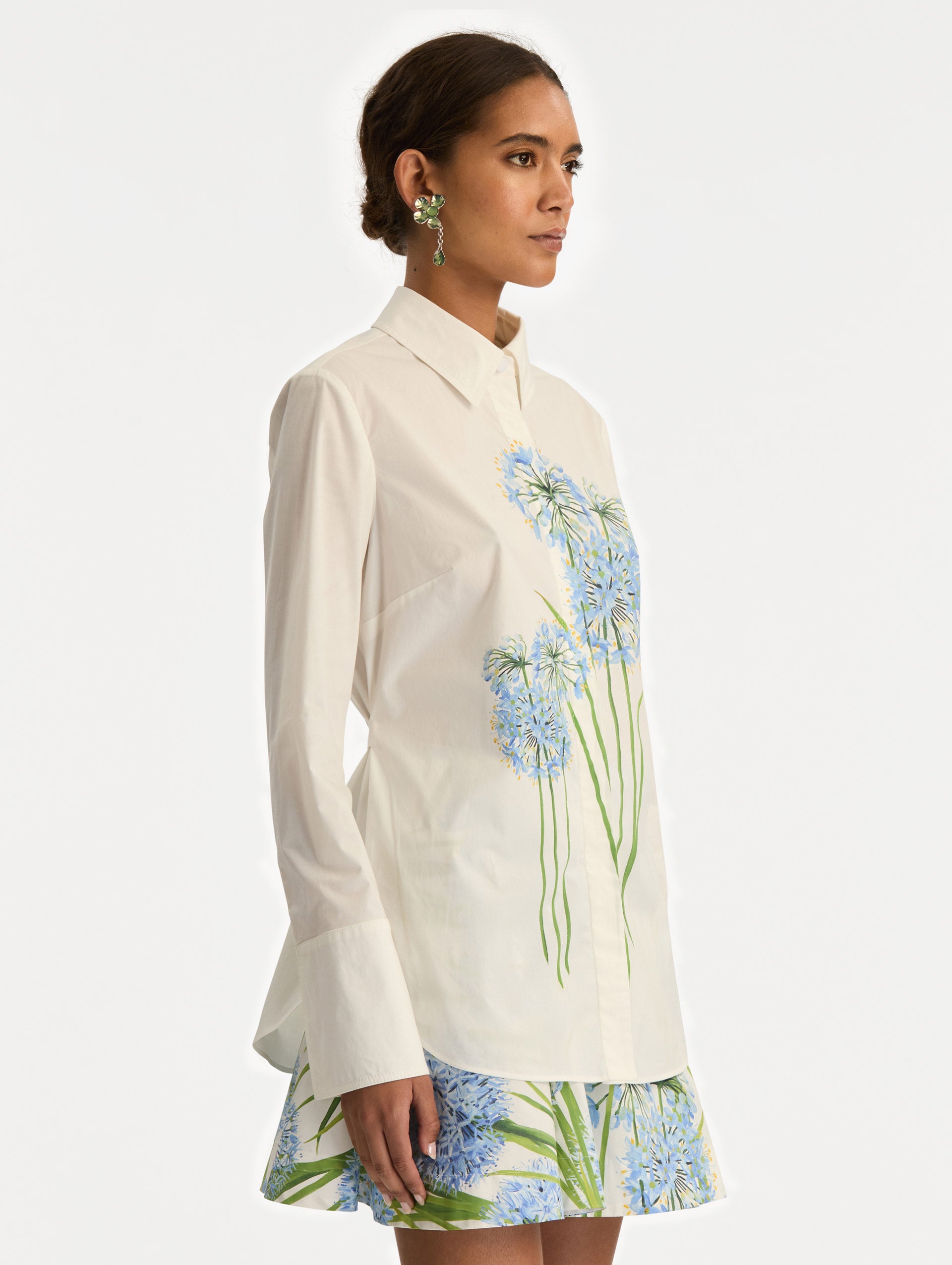 Ivory Allium Cotton Poplin Blouse with long sleeves and blue floral embroidery on the front. Side View.