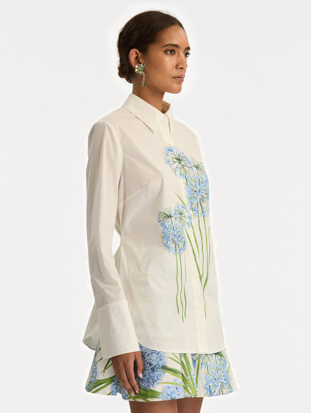 Ivory Allium Cotton Poplin Blouse with long sleeves and blue floral embroidery on the front. Side View.