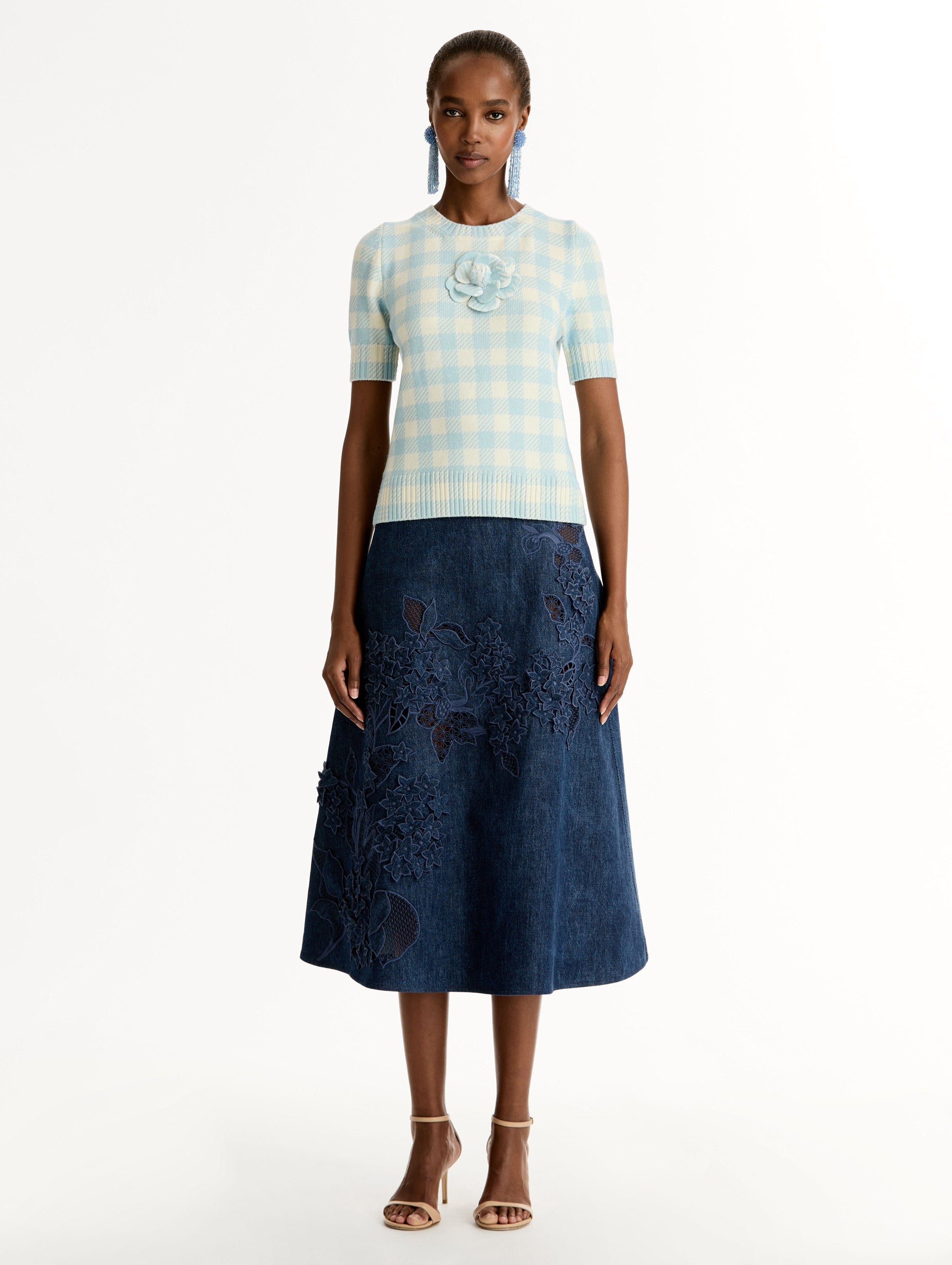 Short sleeve Knit pullover in classic pale blue and white gingham wool. Dimensional floral appliqué at the neckline. Front View. 