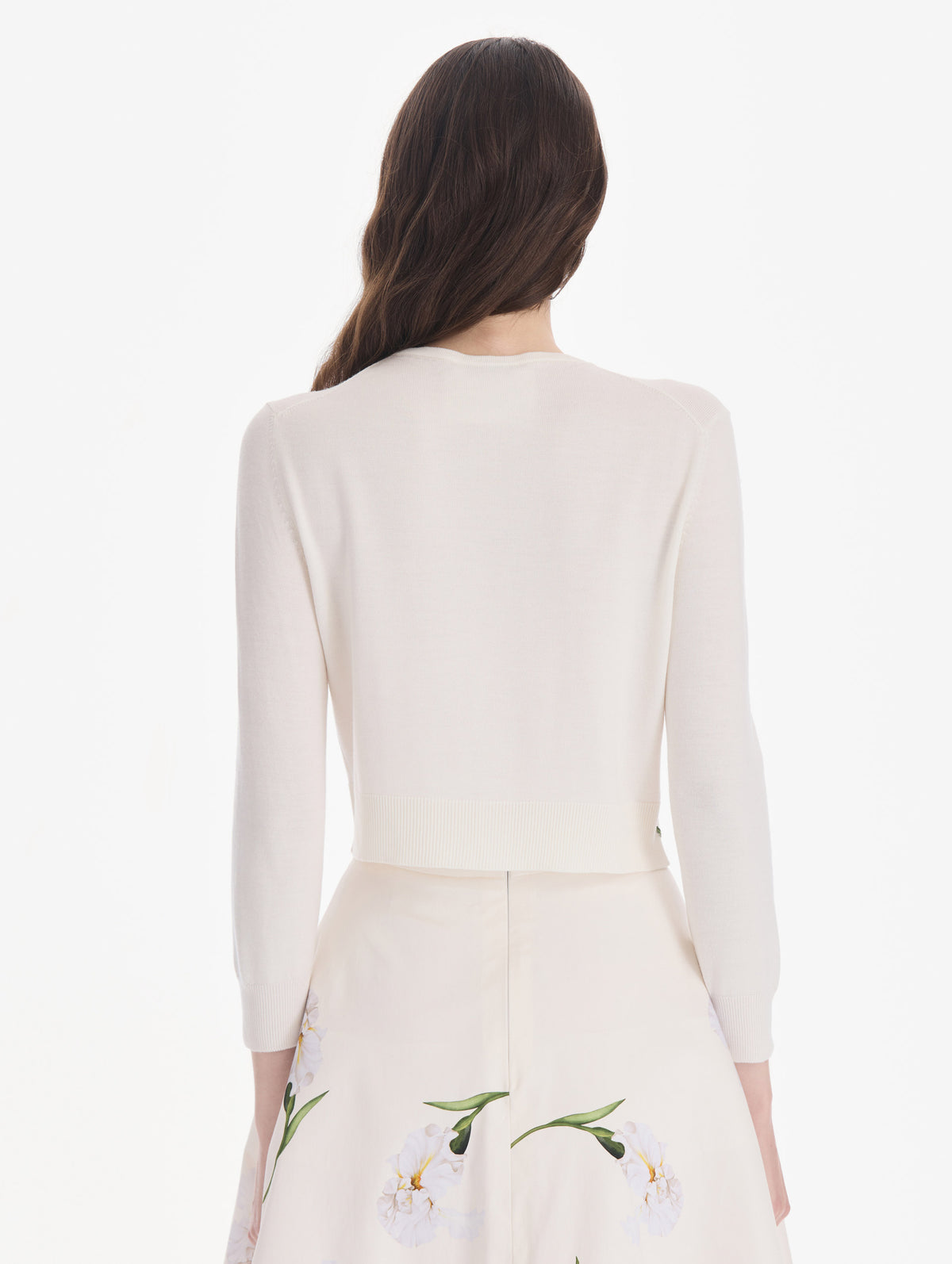 The model is wearing an embroidered cardigan. Back view.