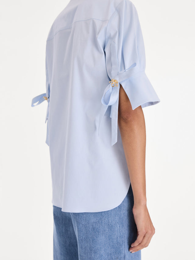 The model is wearing a short sleeve cotton poplin sateen blouse. Zoom view.