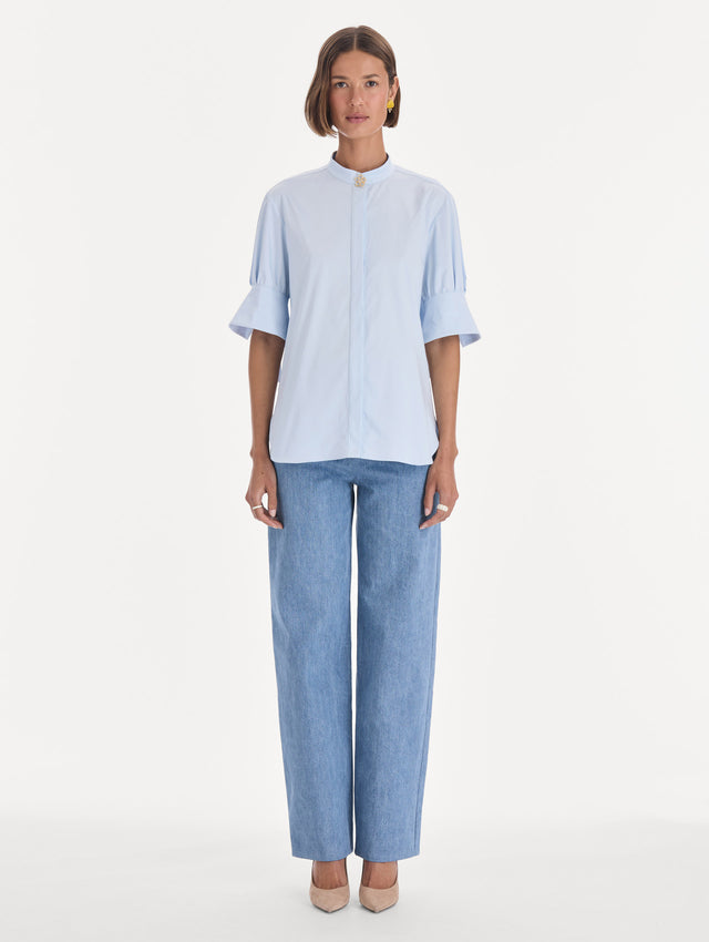 The model is wearing a short sleeve cotton poplin sateen blouse. Front view.