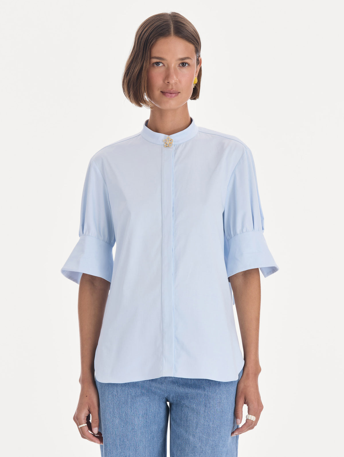 The model is wearing a short sleeve cotton poplin sateen blouse. Front view.