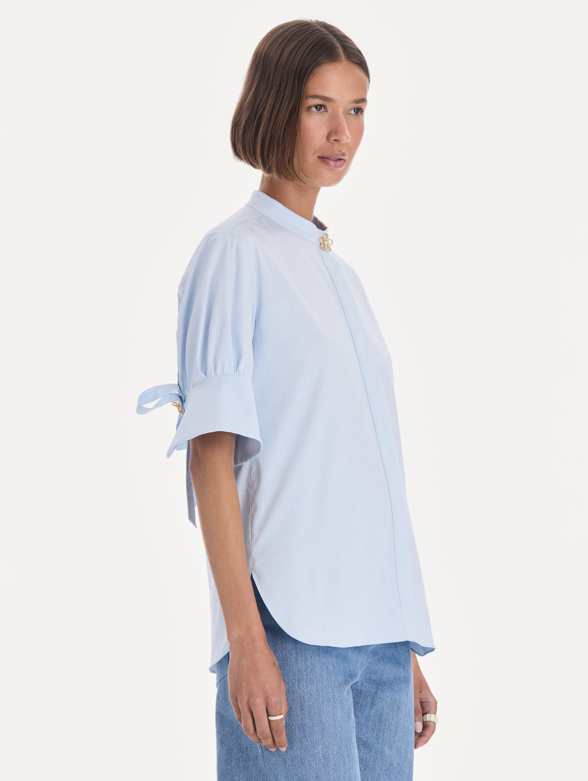 The model is wearing a short sleeve cotton poplin sateen blouse. Side view.
