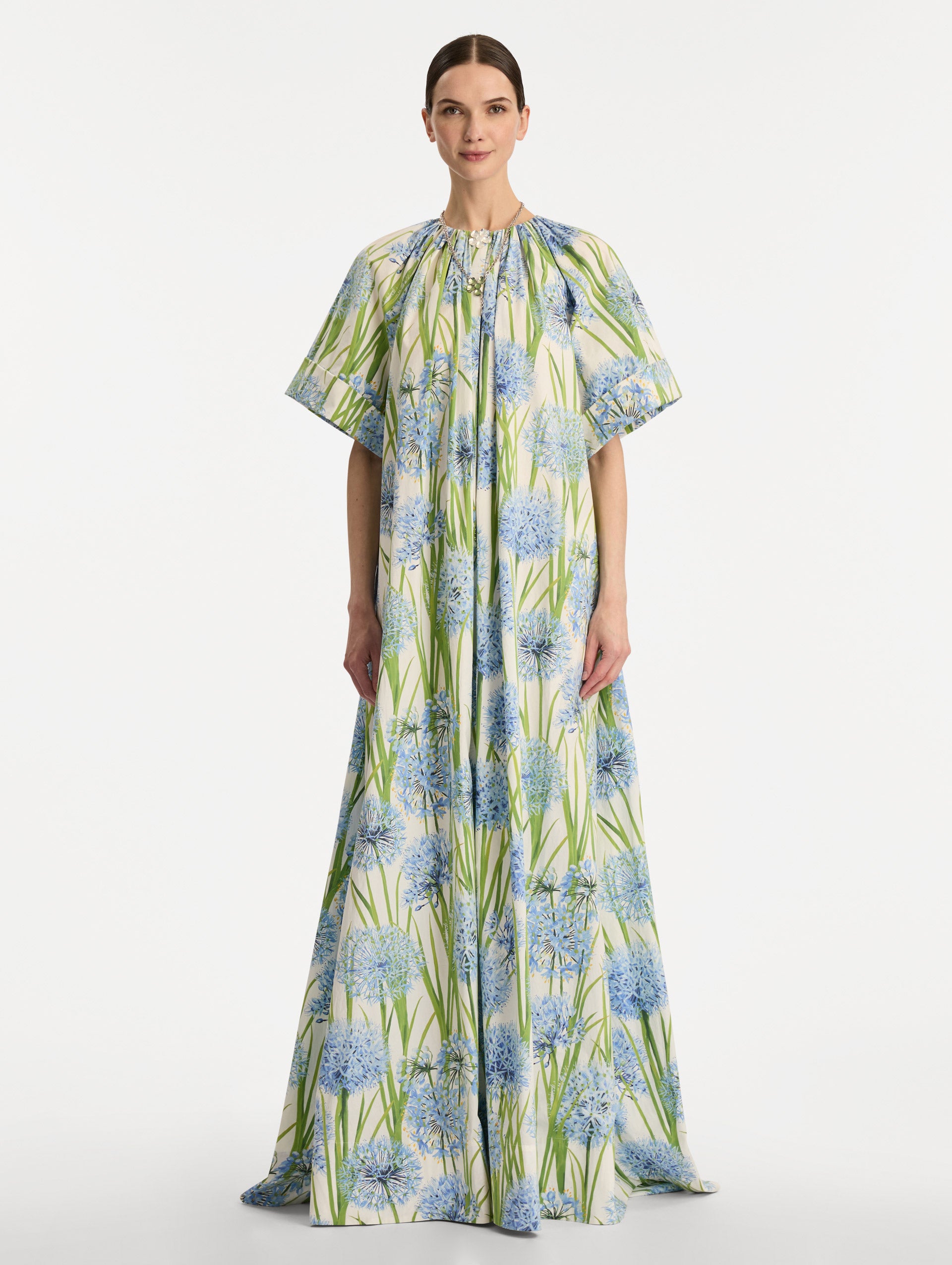 Ivory Allium Cotton Poplin Caftan with short sleeves and gathered neckline, featuring an allover blue floral print with green stems. Front View.