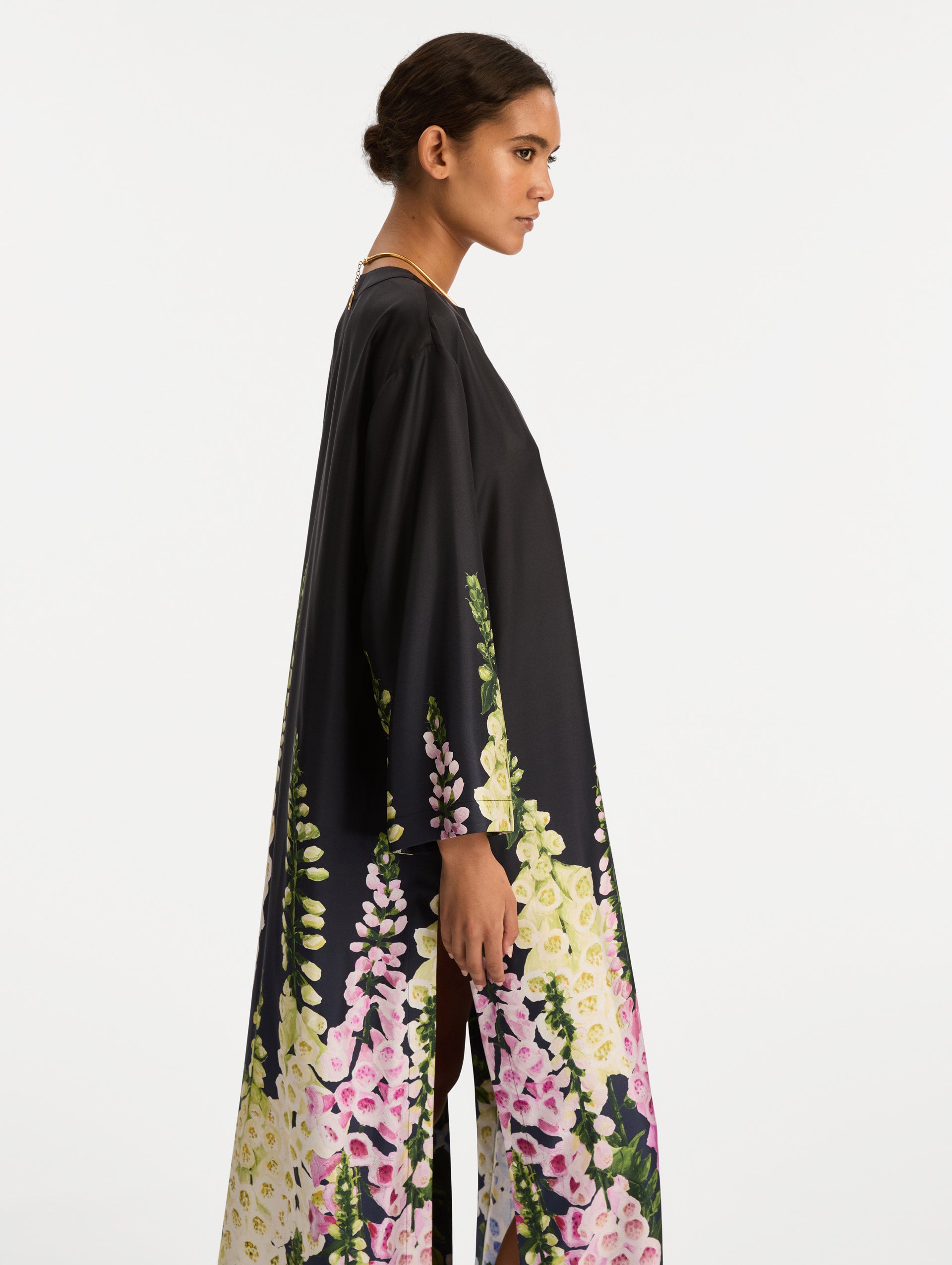 Black Degradé Foxglove Silk Twill Caftan with long sleeves, decorated with multicolor foxglove floral prints along the hem and sleeve edges. Zoom View.