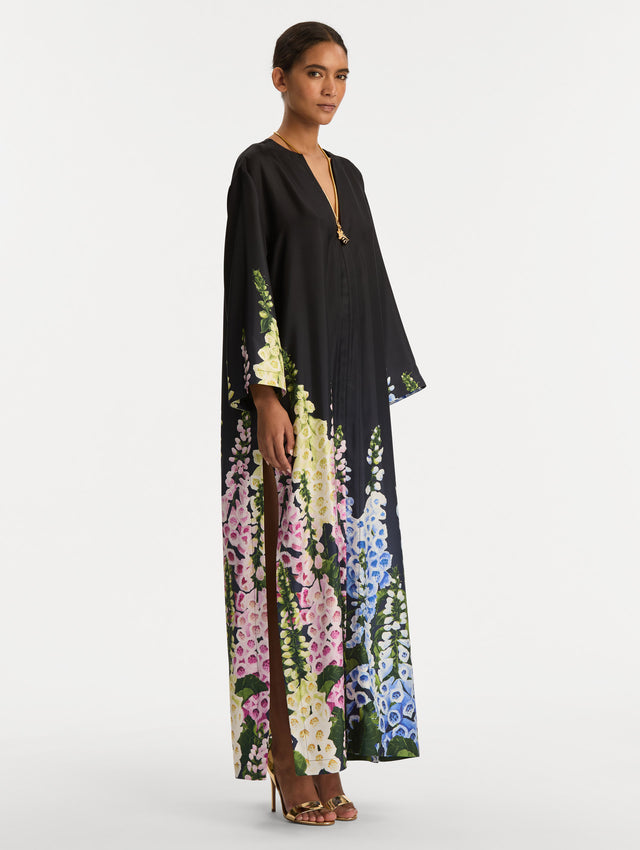 Black Degradé Foxglove Silk Twill Caftan with long sleeves, decorated with multicolor foxglove floral prints along the hem and sleeve edges. Side View.