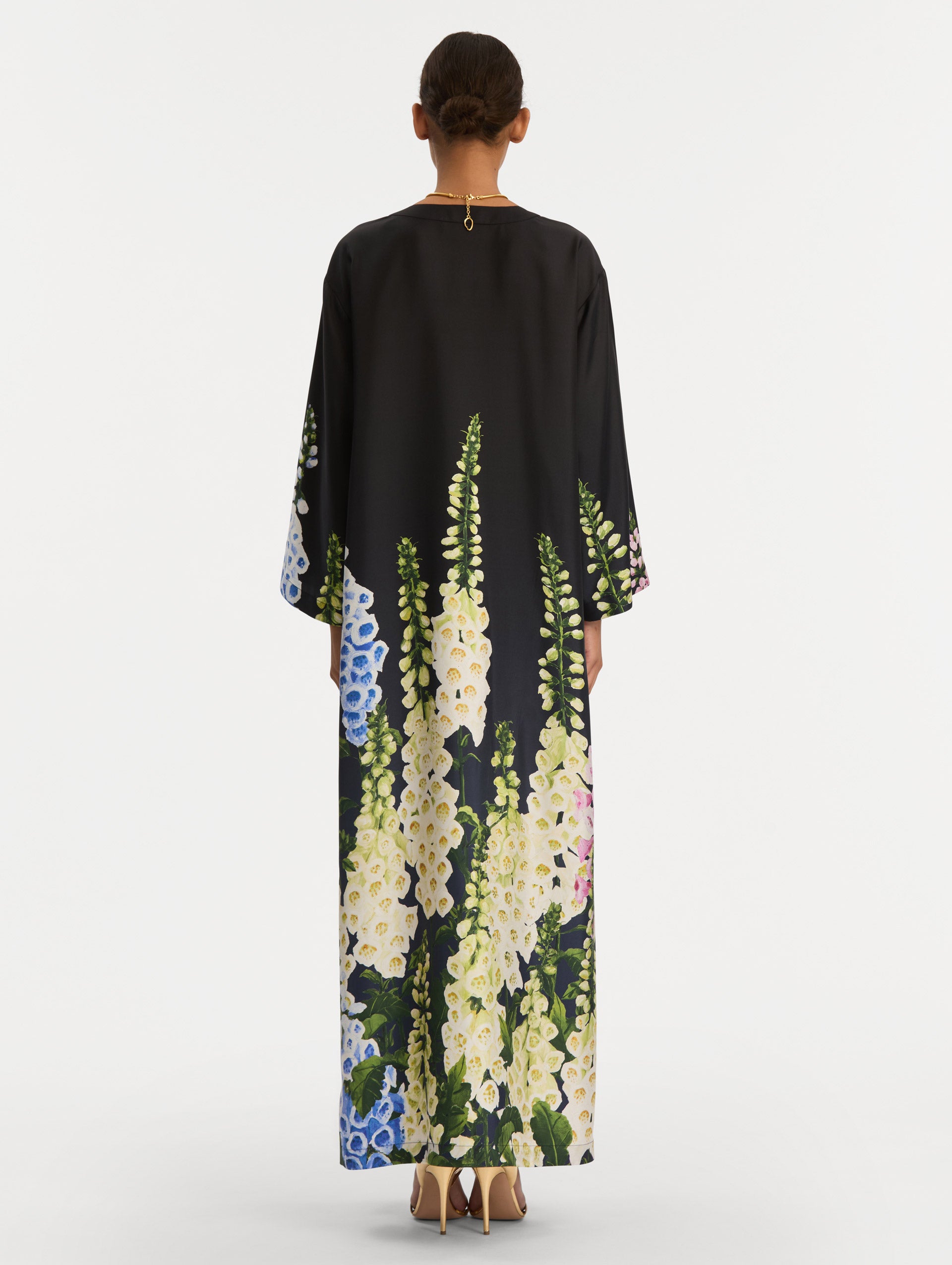 Black Degradé Foxglove Silk Twill Caftan with long sleeves, decorated with multicolor foxglove floral prints along the hem and sleeve edges. Back View.