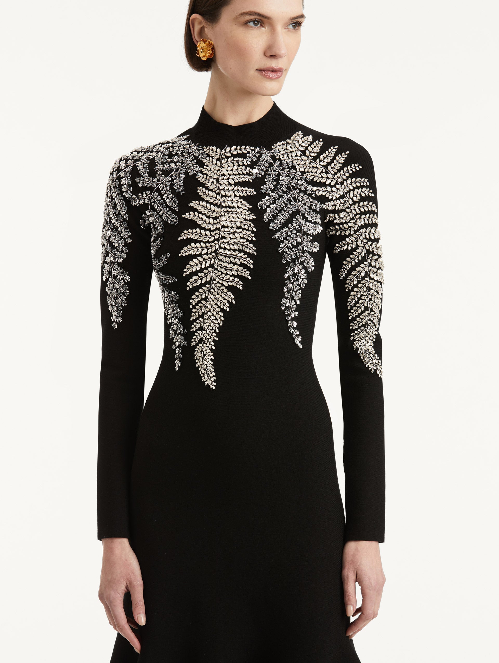 Zoomed in image of metallic fern embroidery along the mock neck and shoulders. 