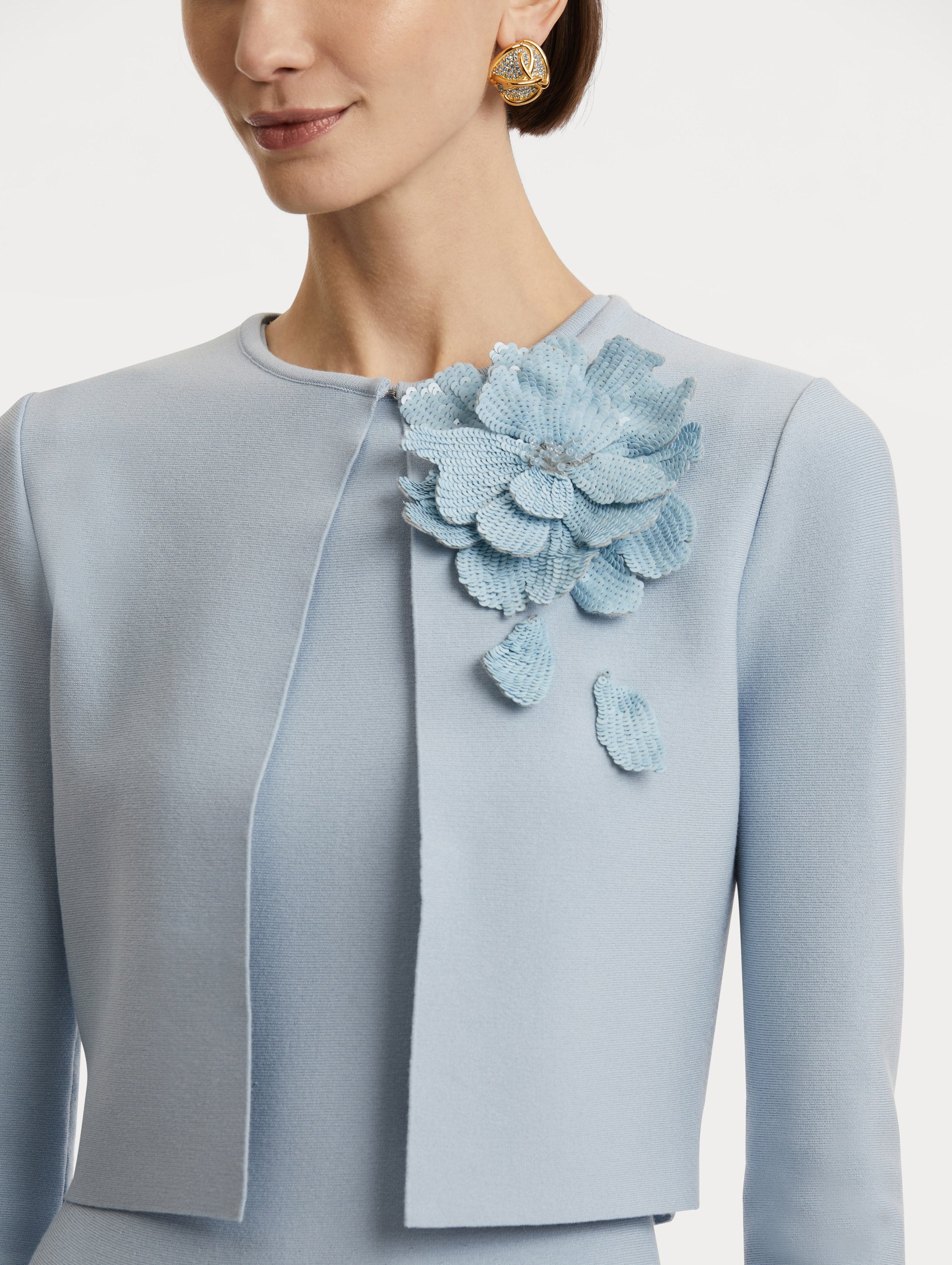 Zoomed in image of light blue sequin peony appliqués at the neckline. 