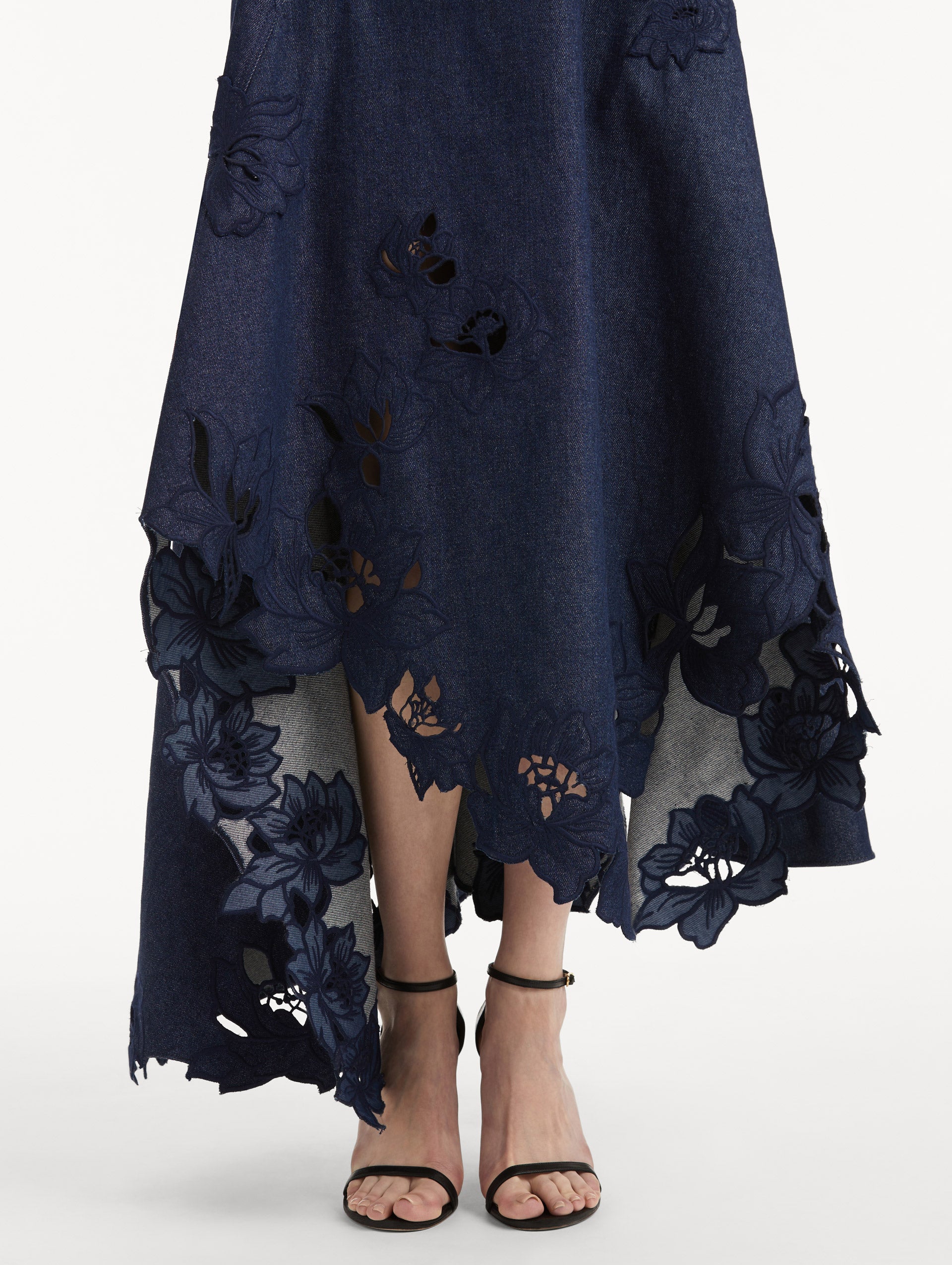 Zoomed in image of peony threadwork cutouts on a denim dress with an asymmetrical hem. 