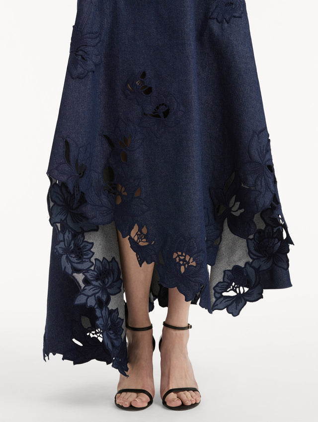 Zoomed in image of peony threadwork cutouts on a denim dress with an asymmetrical hem. 