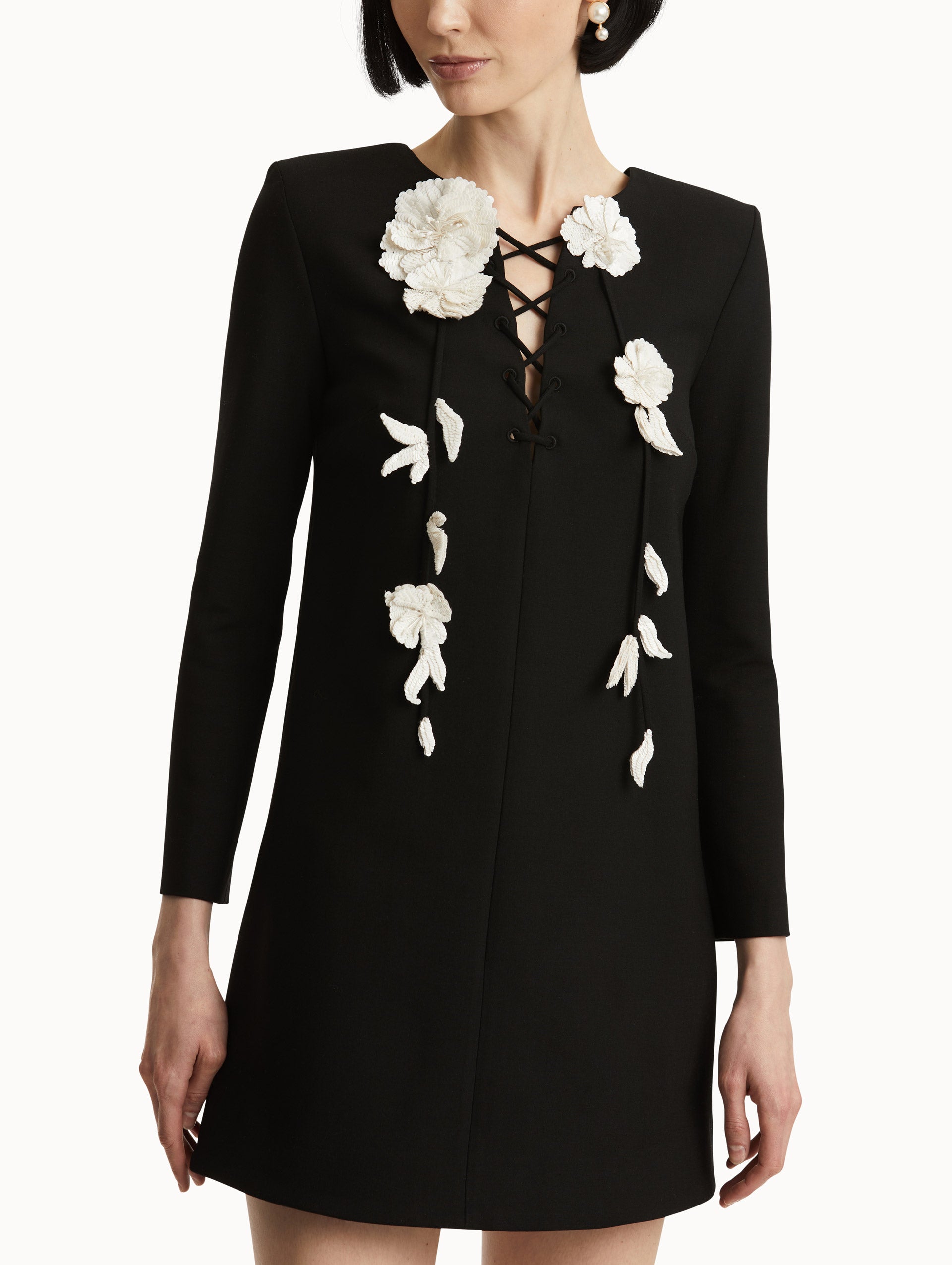 Zoomed in image of lace-up neckline and white embroidered sequin floral appliqués. 