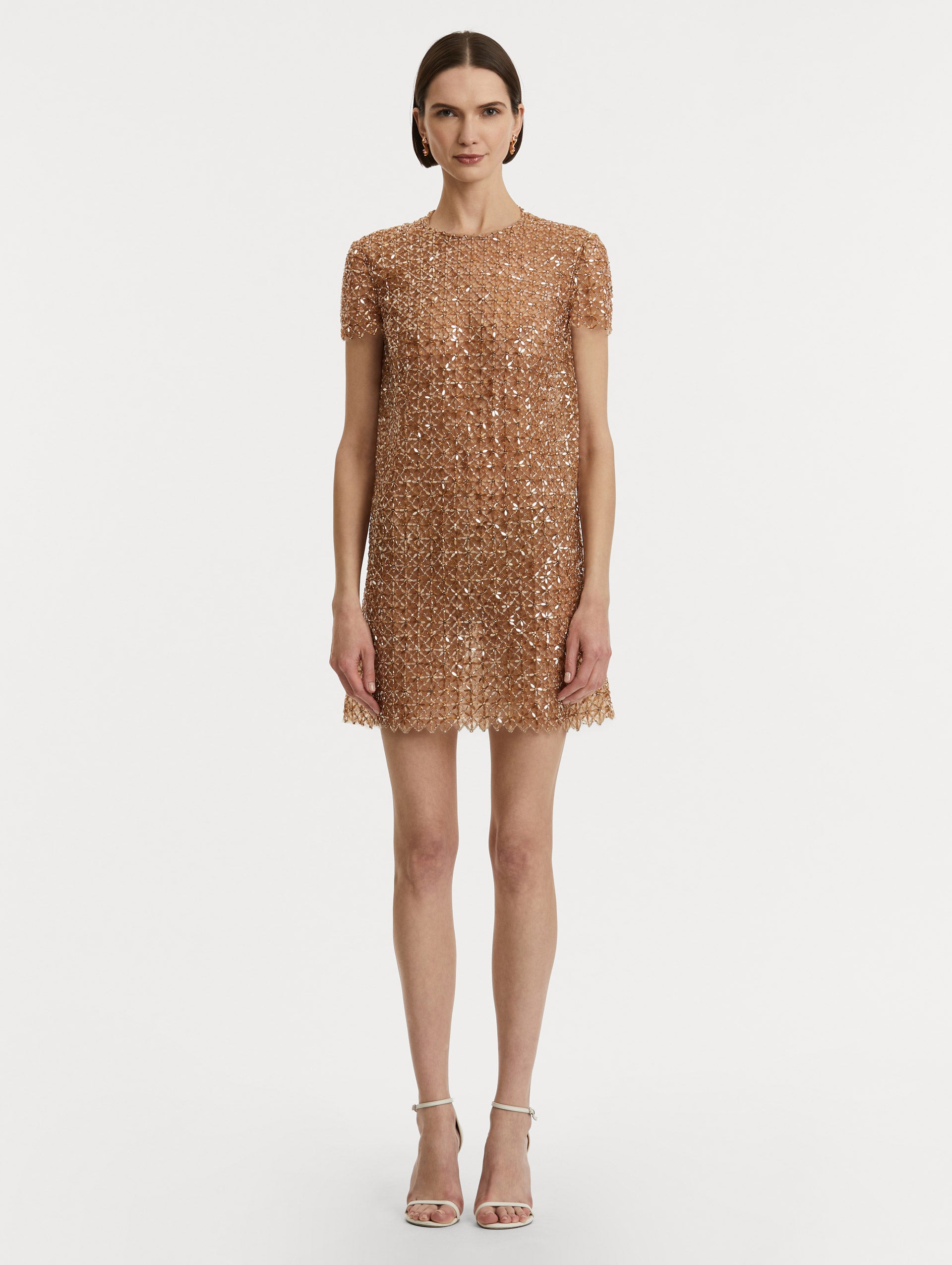 Full body front view of model wearing short sleeve dress with amber glass blooms in a grid pattern. 