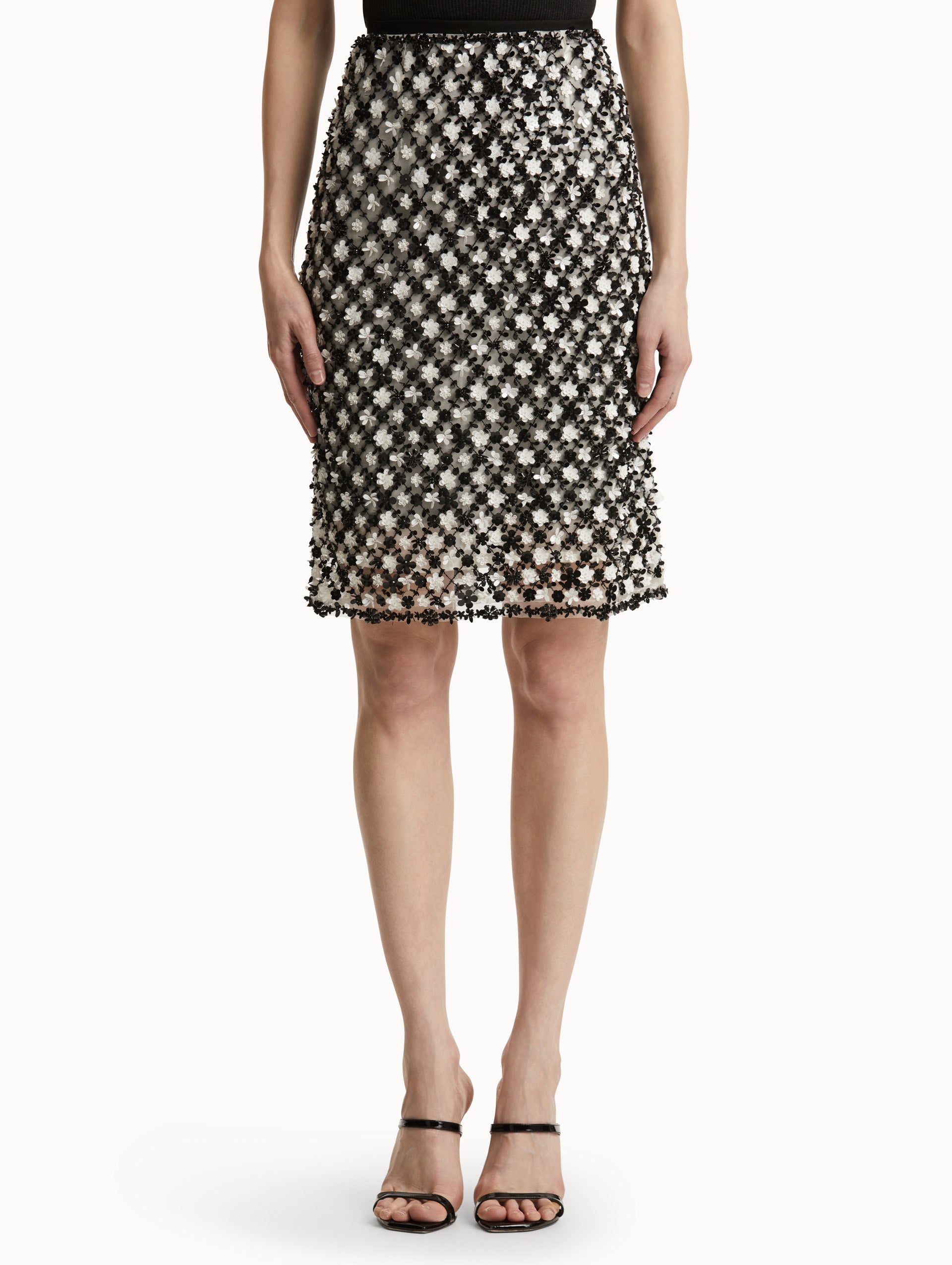 Front view of model wearing a high waisted black and ivory floral embroidered pencil skirt that follows a tweed pattern.  