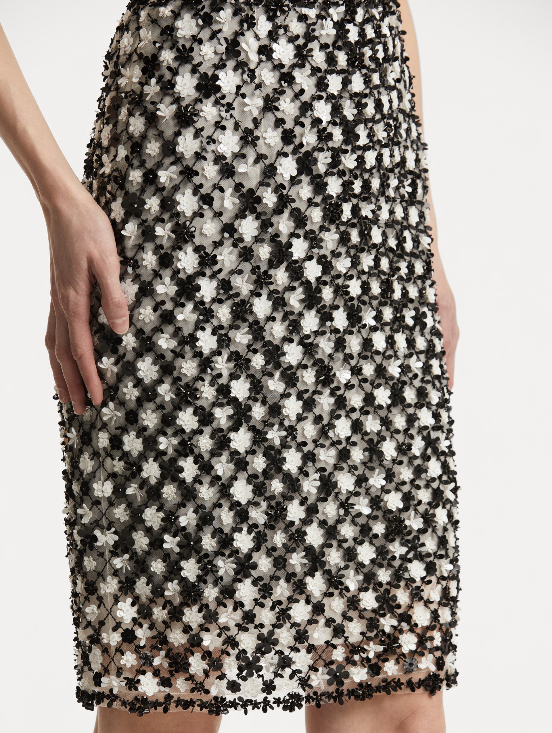 Zoomed in image of high waisted black and ivory floral embroidered pencil skirt that follows a tweed pattern.  