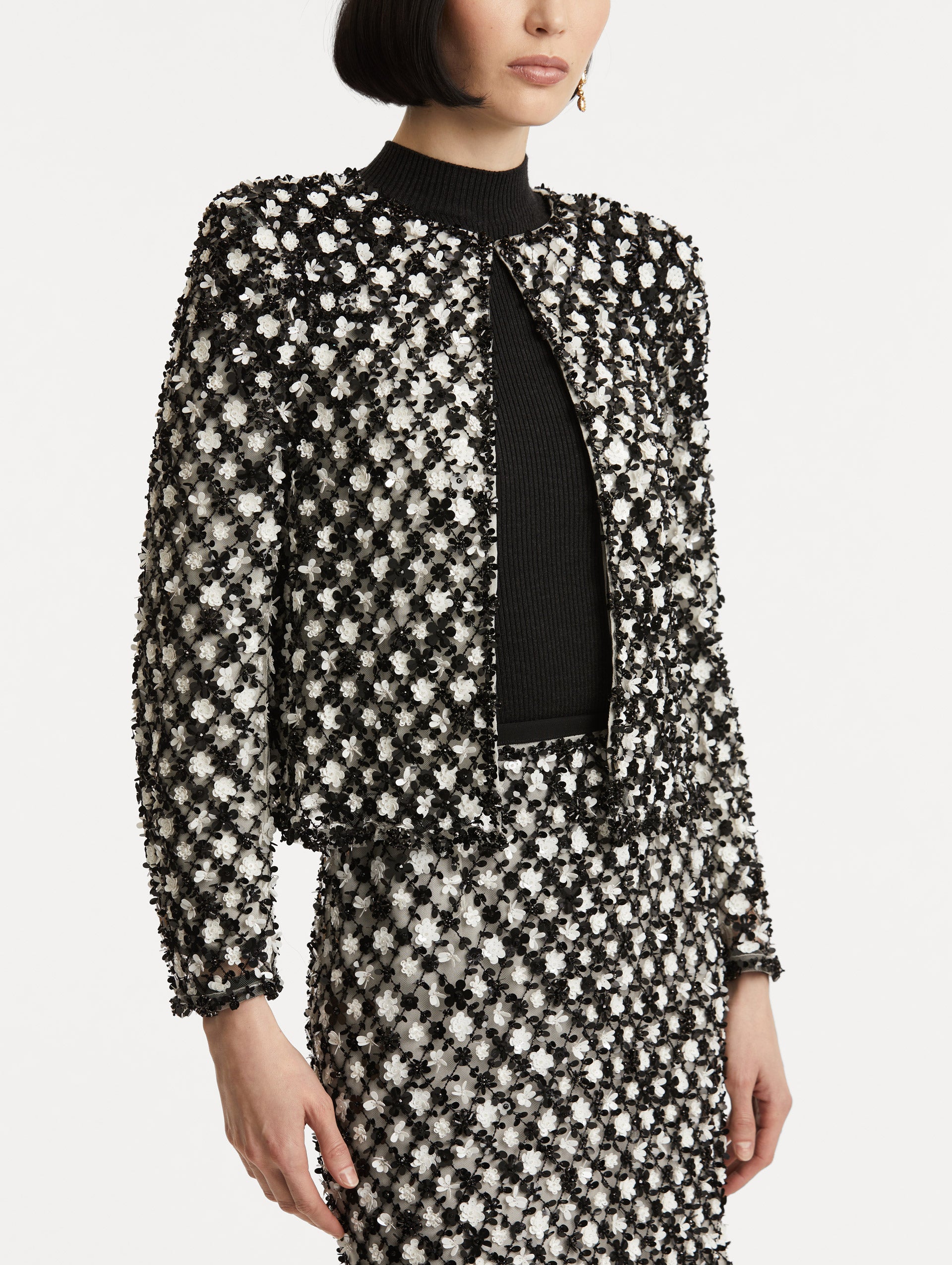 Zoomed in image of black and ivory long sleeve jacket with sequin embroidery, where florets create a tweed pattern.