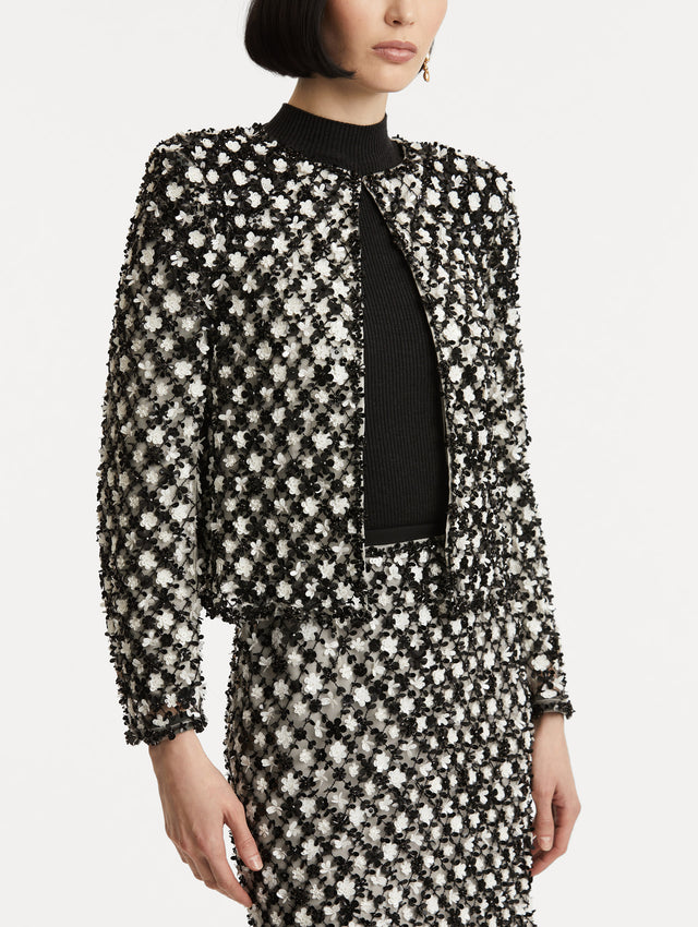 Zoomed in image of black and ivory long sleeve jacket with sequin embroidery, where florets create a tweed pattern.