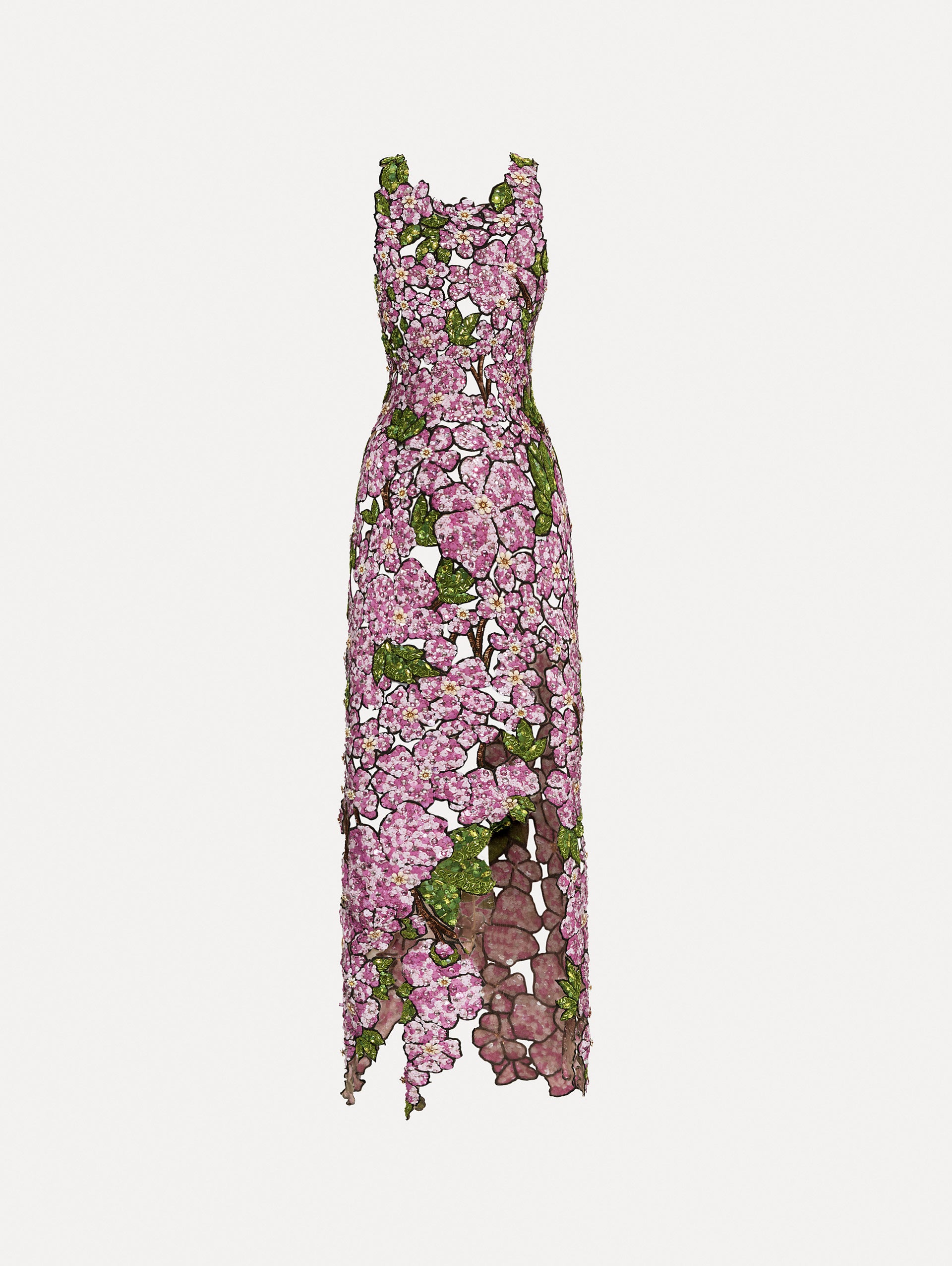 Sleeveless cocktail dress with embroidered pink flowers and green leaves on a sheer tulle base. While the skirt follows a asymmetrical hem