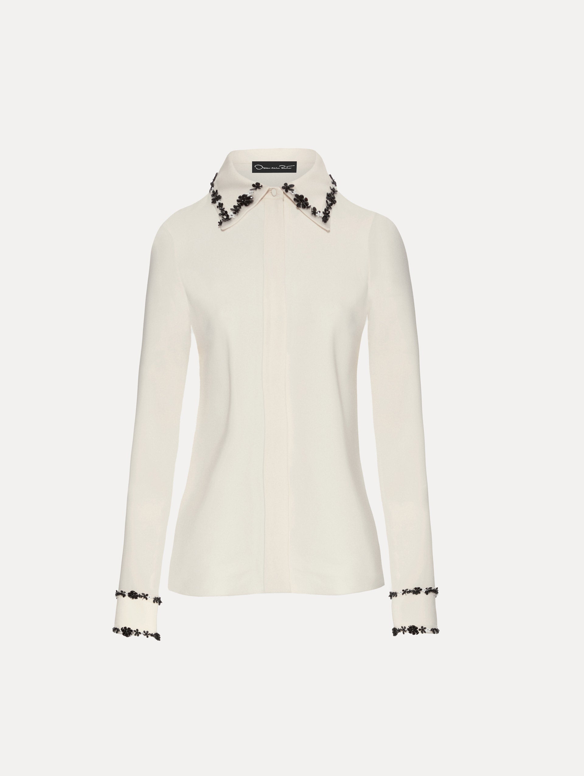 Ivory blouse with black sequin flower embroidery trace the trim with a spread collar.