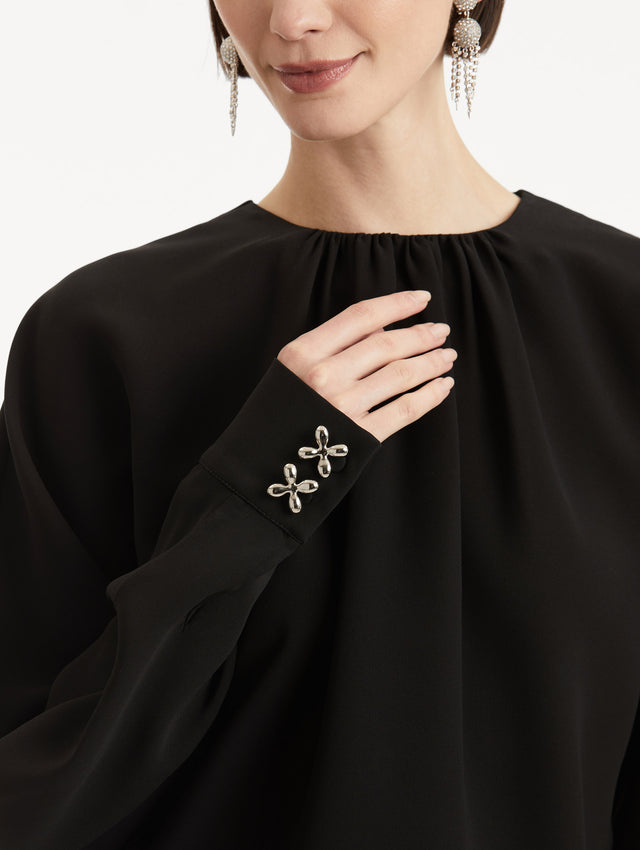 Zoomed in image of crystal floral cuff appliques on black long sleeve top. 