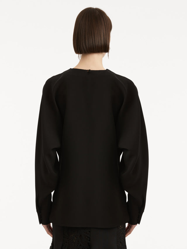 Back view of model wearing black long sleeve top.