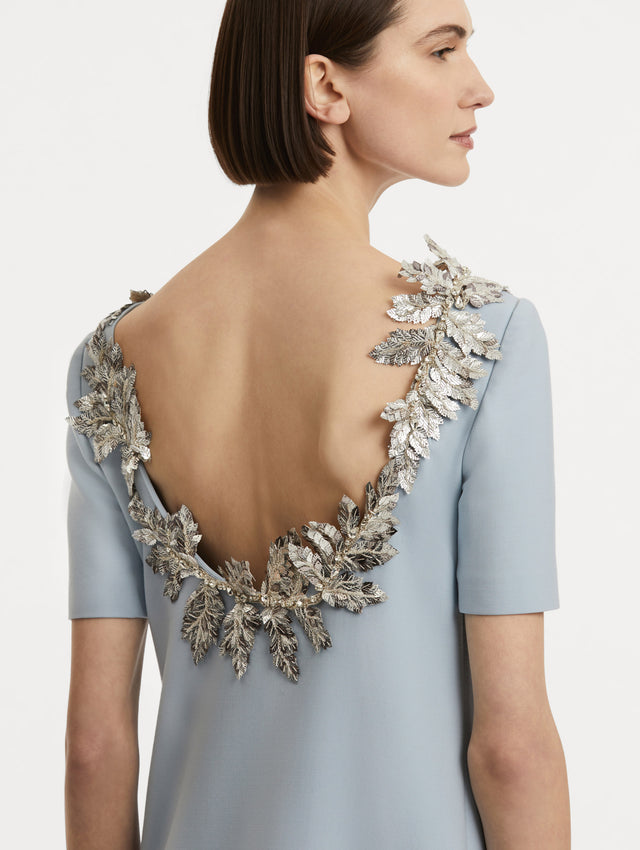 Zoomed in back view of silver fern embroidery sequins framing the scoop back with light blue short sleeves. 