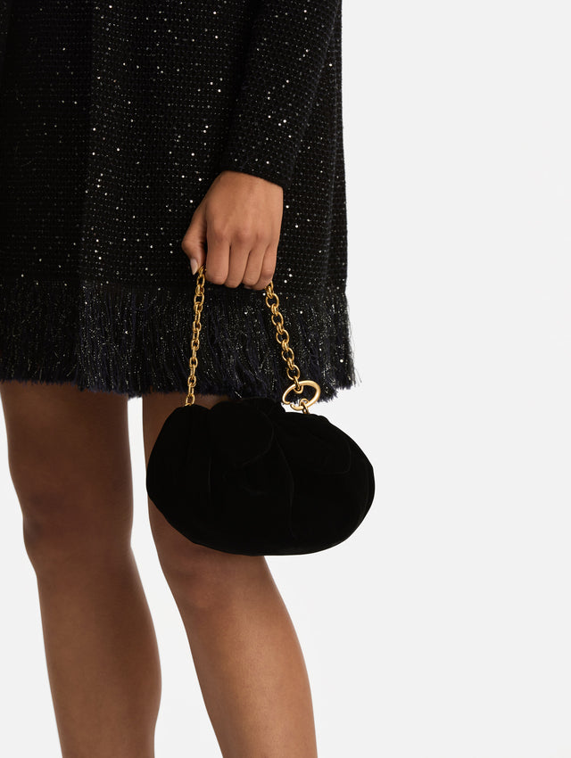 The Velvet Clutch in black features fabric folding, where the velvet is gathered and secured with a voluminous bow. 