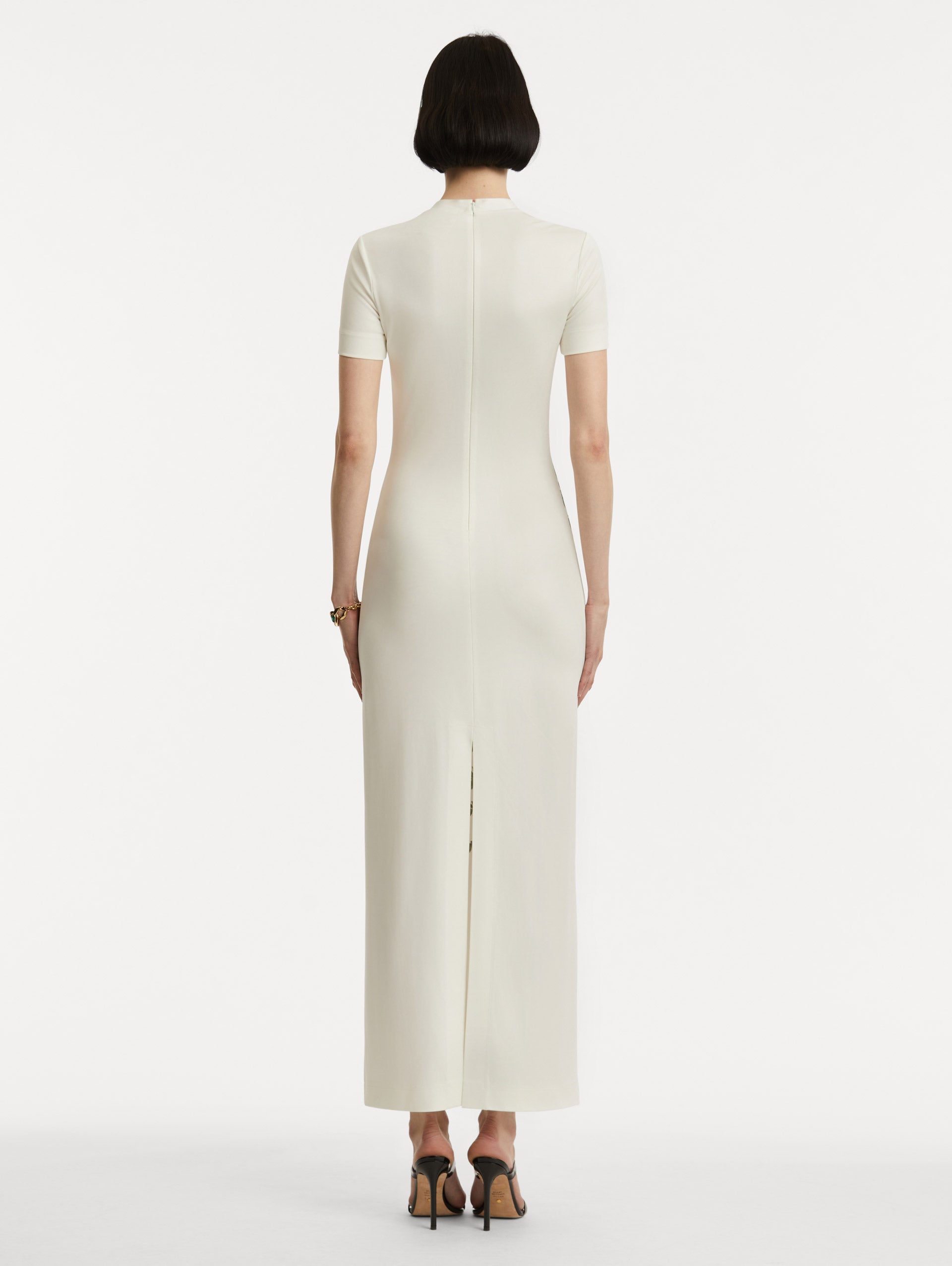 Full body back view of model wearing a short-sleeve jersey dress with a ivory base and concealed zipper. 