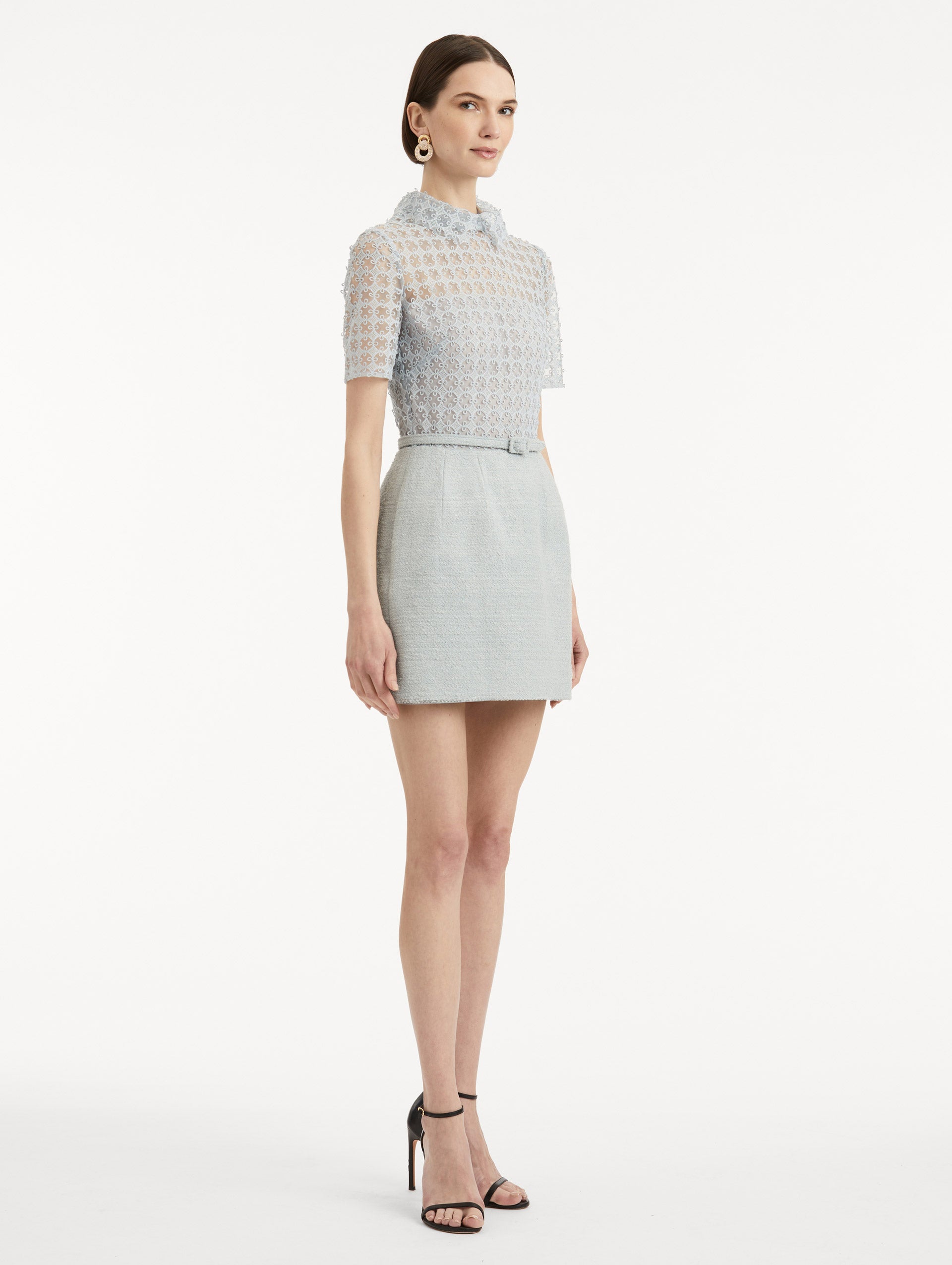 Side view of model wearing blue quartz tweed dress with lace top, short sleeves, collar, and matching tweed belt. 