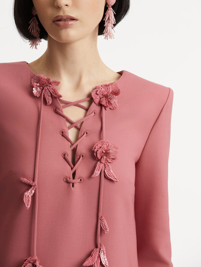 Zoomed in detail of lace up floral neckline on the pink long sleeve caftan.