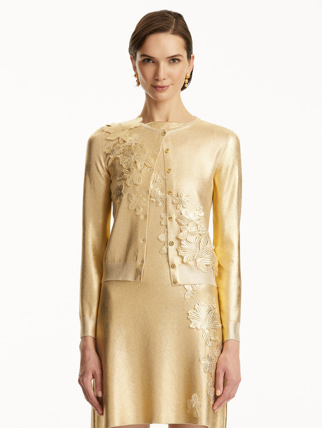The model is wearing a Metallic gold cardigan with cherry blossom embroidery, over a matching dress. Front view