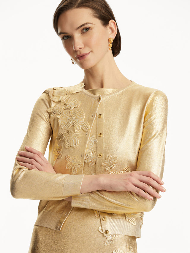 The model is wearing a Metallic gold cardigan with cherry blossom embroidery, over a matching dress. Zoom view