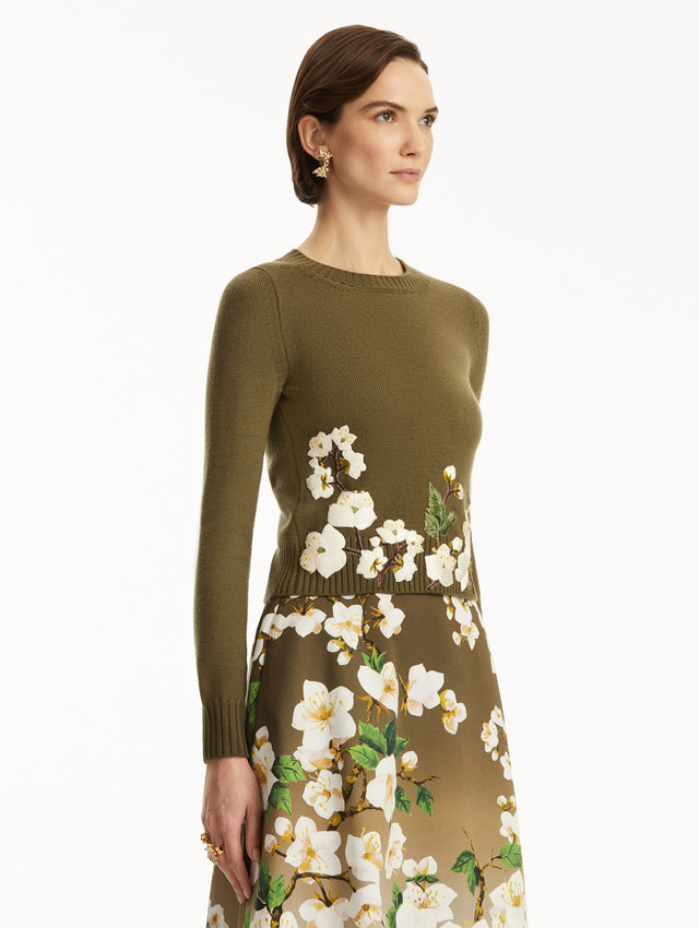 The model is wearing a Khaki pullover with white cherry blossoms embroidered in the bottom, over a matching dress. Side view