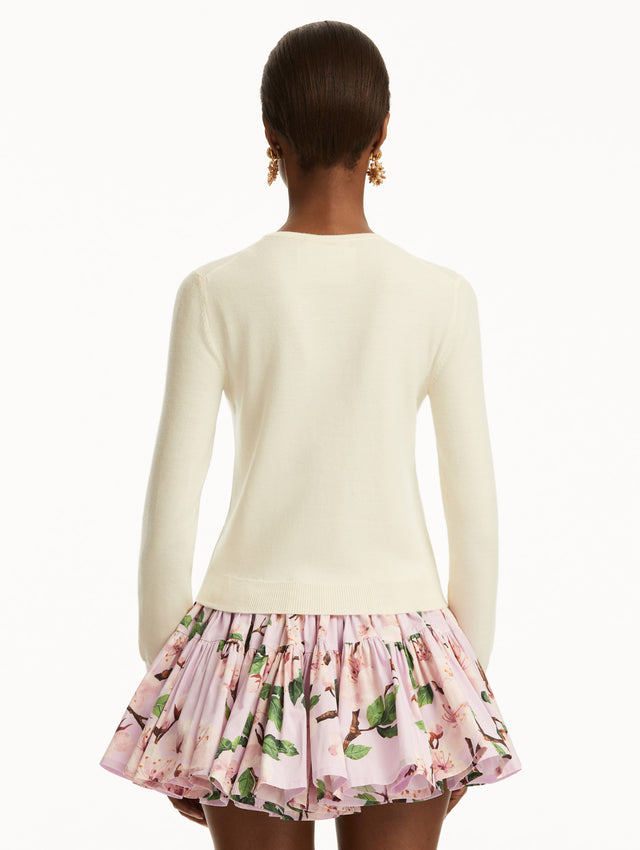 The model is wearing a white cardigan with pink cherry blossoms embroidered over a pink cherry blossom mini dress. Back View