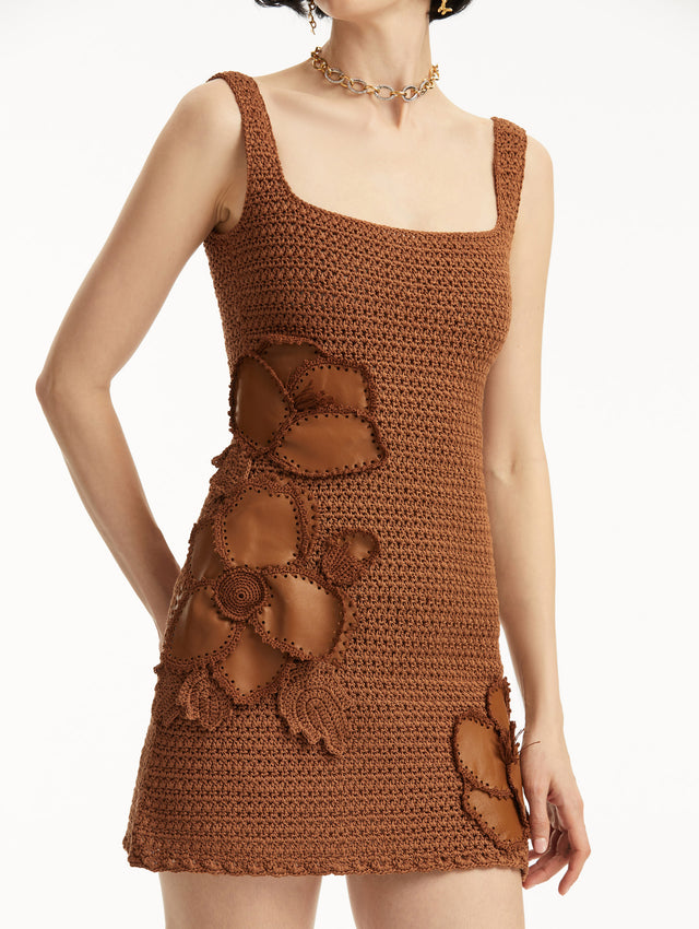 The model is wearing a brown sleeveless crochet mini dress with three-dimensional leather cherry blossom appliques. Zoom view