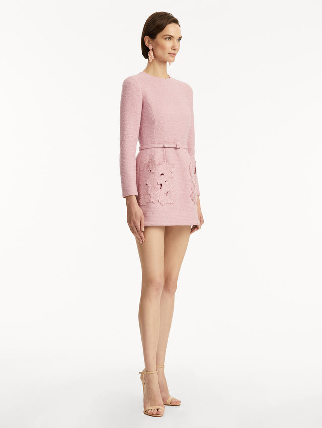 Model wearing long sleeve mini tweed dress in light pink, with a matching belt and cherry blossom cut-out pockets. Side view