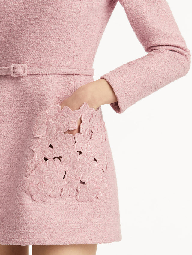 Model wearing long sleeve mini tweed dress in light pink, with a matching belt and cherry blossom cut-out pockets. Zoom view