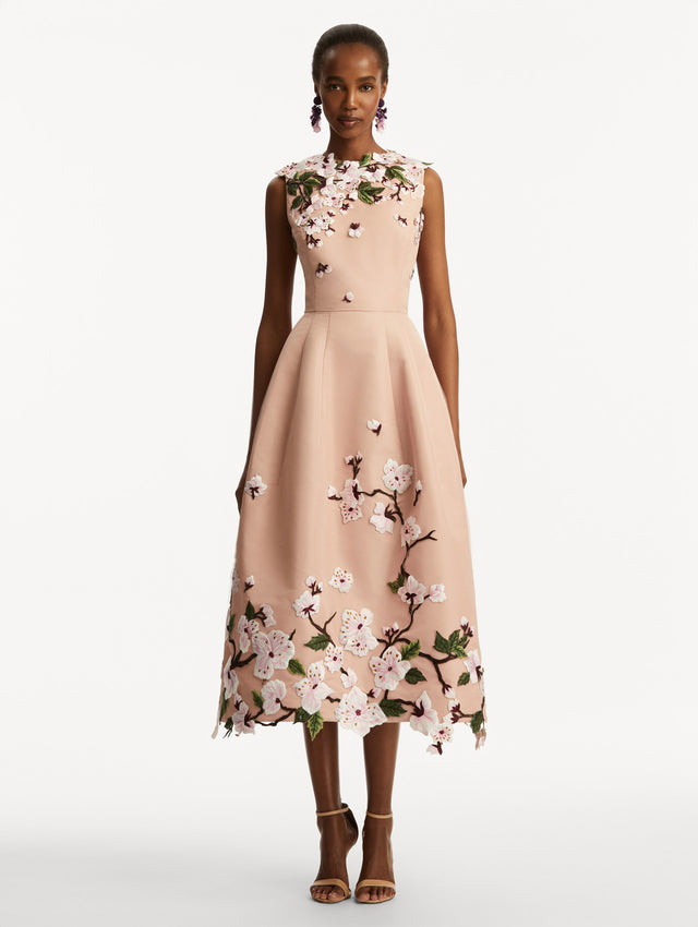 Model wearing a blush pink sleeveless dress with cherry blossoms embroidered throughout the top and bottom. Front view