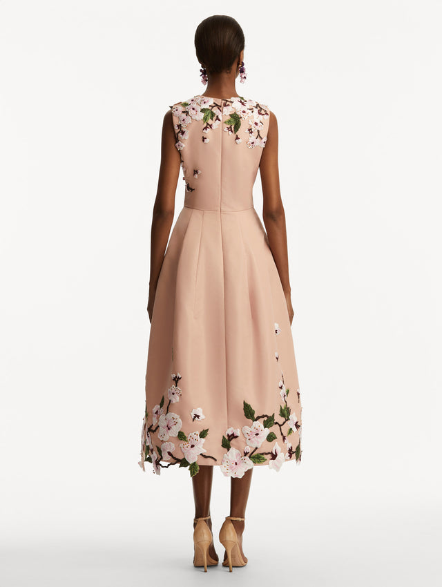 Model wearing a blush pink sleeveless dress with cherry blossoms embroidered throughout the top and bottom. Back view
