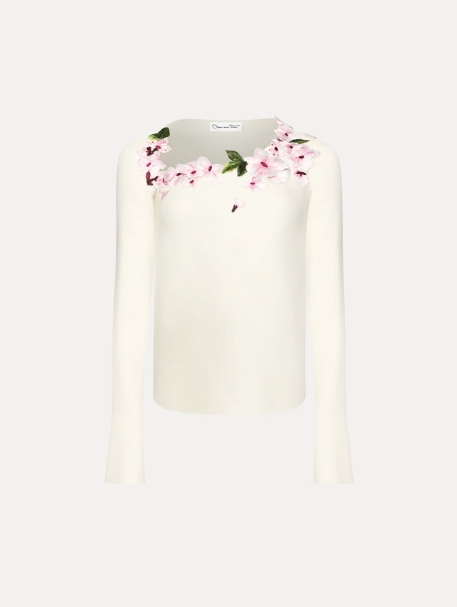 White blouse with cherry embroidered detail around the neck.