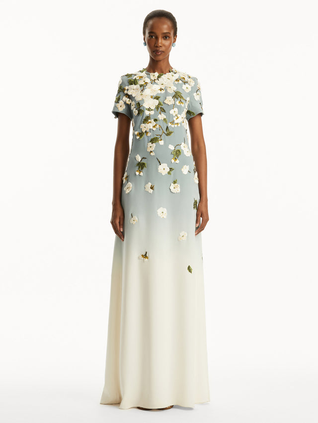 Model wearing Ombre light blue to white gown with short sleeves and white cherry blossoms embroidered. Front View