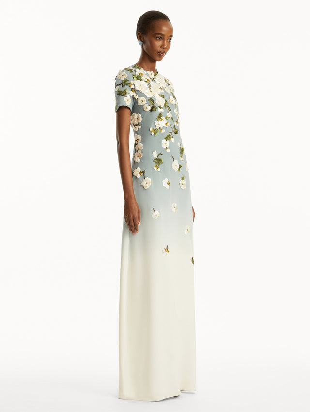 Model wearing Ombre light blue to white gown with short sleeves and white cherry blossoms embroidered. Side View