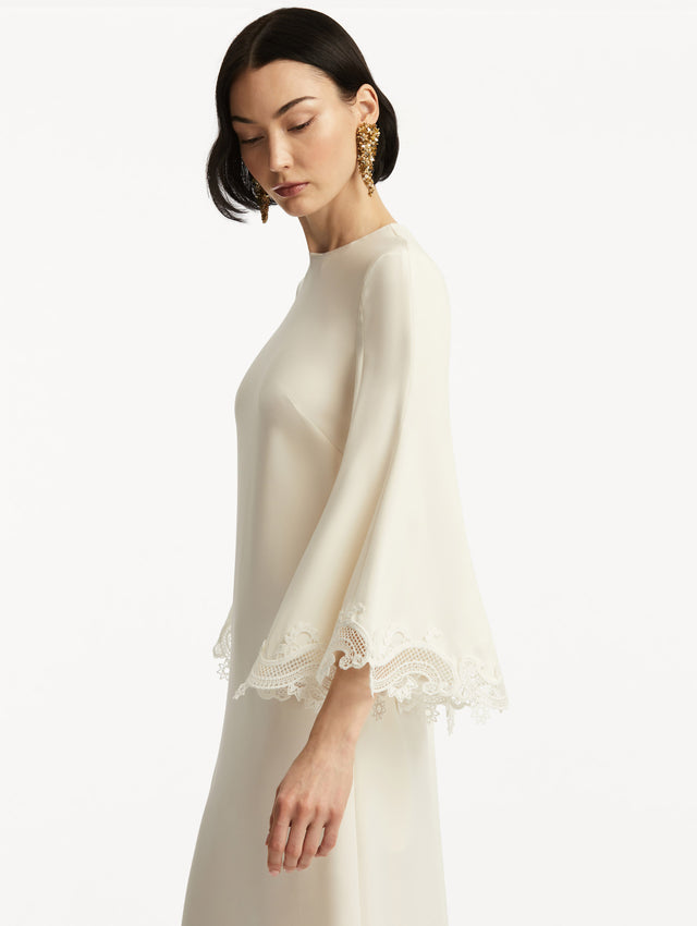 Model wearing white long sleeve caftan with lace detail on the cuff of the bell sleeves. Zoom view.
