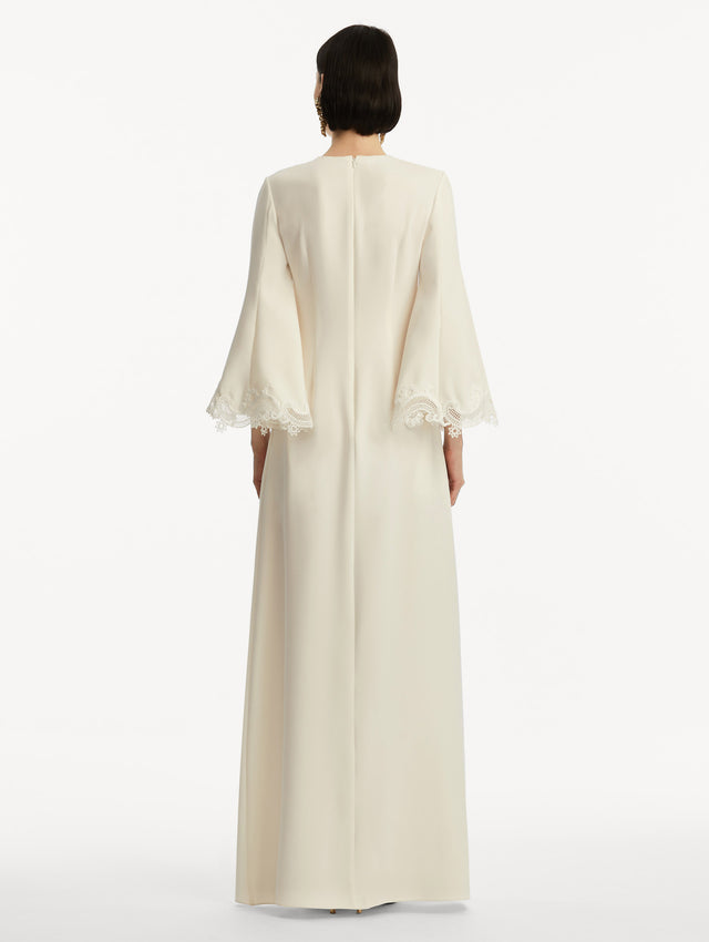 Model wearing white long sleeve caftan with lace detail on the cuff of the bell sleeves. Back view.