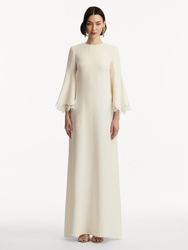 Model wearing white long sleeve caftan with lace detail on the cuff of the bell sleeves. Front view.