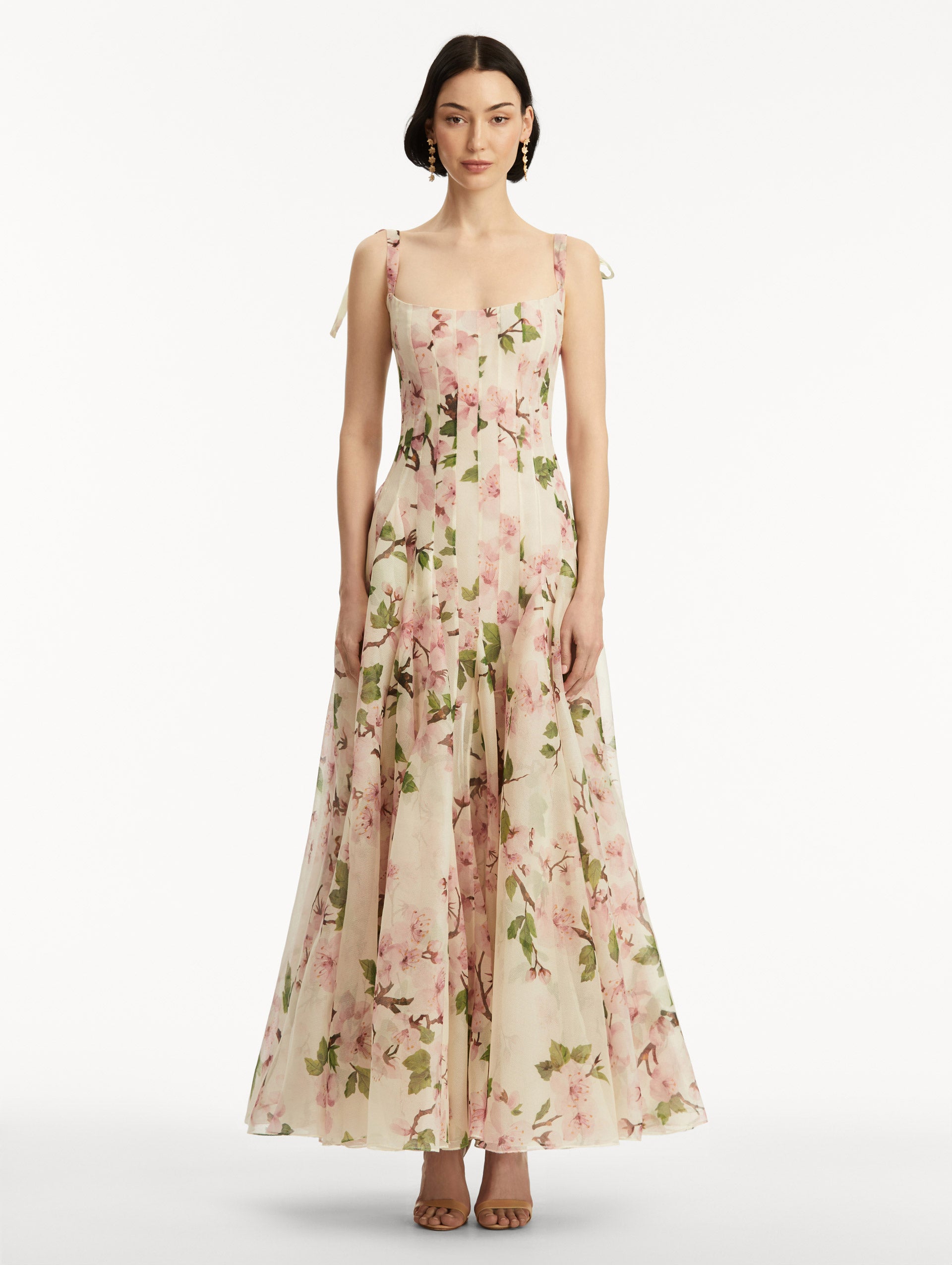 White sleeveless gown with pink cherry blossoms, and bow detail in the straps. Front view.