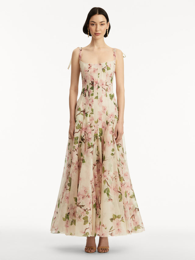 White sleeveless gown with pink cherry blossoms, and bow detail in the straps. Front view.