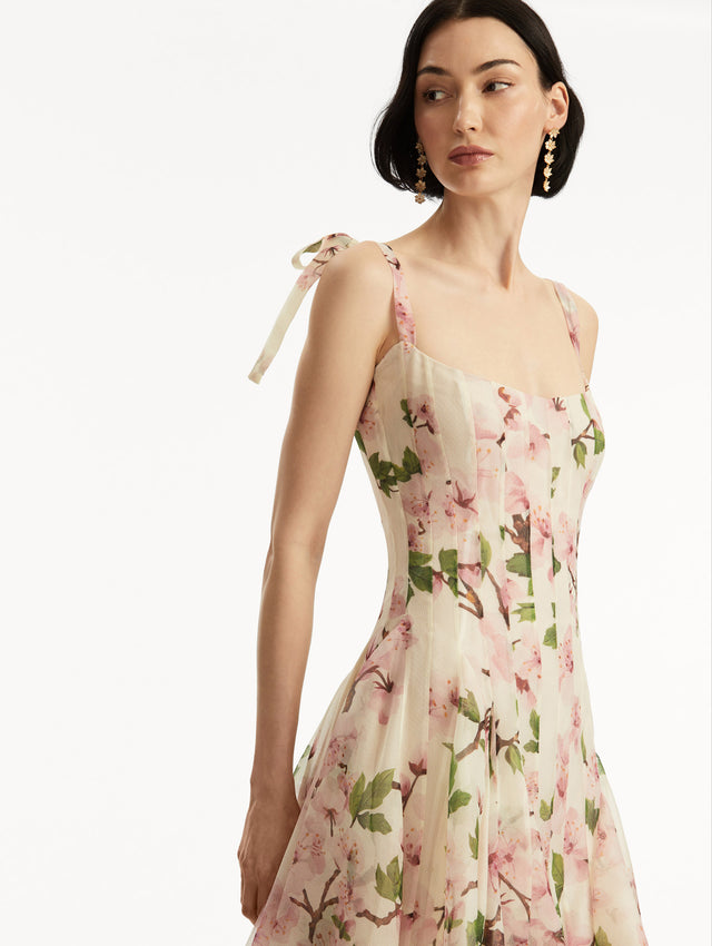 Model wearing White sleeveless gown with pink cherry blossoms, and bow detail in the straps. Zoom view.