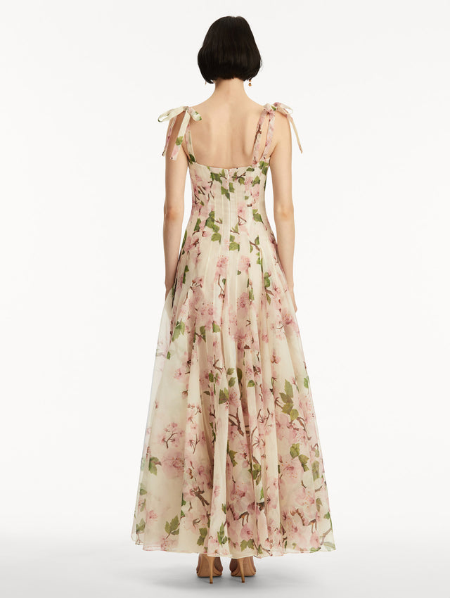 White sleeveless gown with pink cherry blossoms, and bow detail in the straps. Back view.